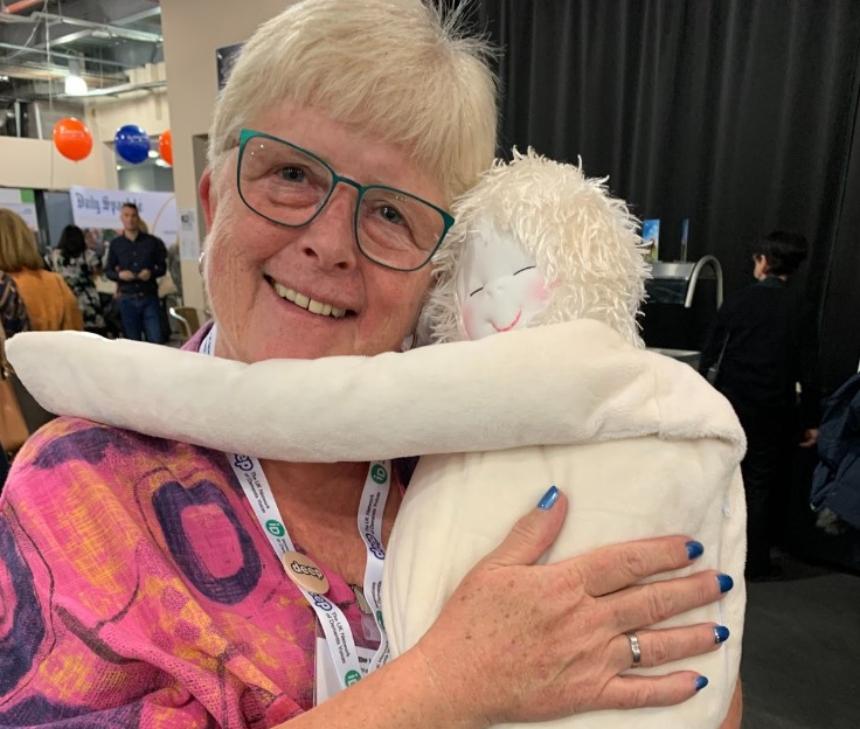 Chris at the Alzheimer Europe conference cuddling HUG™, a soft comforter