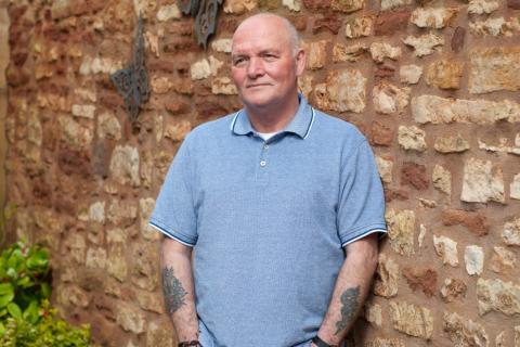 A man stands in front of a wall with his hands in his pocket